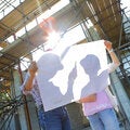 Two people reviewing blueprints at a construction site