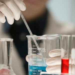 Scientist dropping liquid in beakers