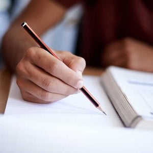 person holding pencil writing on paper