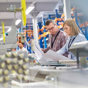 man and woman in factory looking at plans