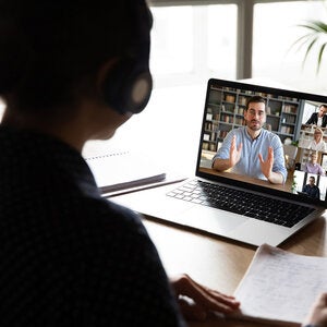 person sitting at a desk looking at zoom meeting on laptop