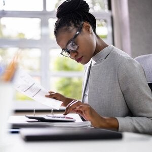 A woman studying paperwork and using a calculator