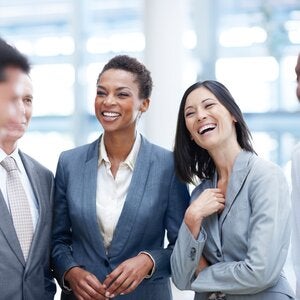 two women in suits networking with male colleagues