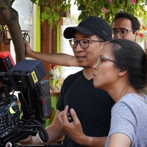 two people next to a film camera discussing film direction