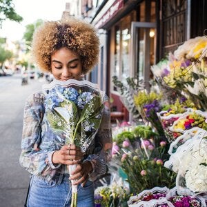 woman smelling hydrangeas outside a flower shop