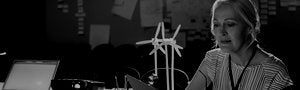 woman holding clipboard and wind turbine on desk