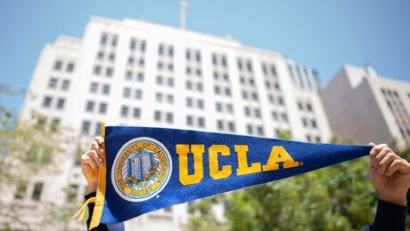 UCLA's downtown Los Angeles Trust building, with hands holding a pennant in foreground