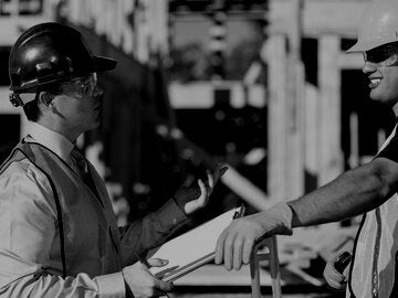 Foreman talking to construction worker on job site.