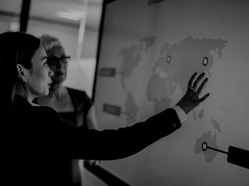 two business women looking at world map