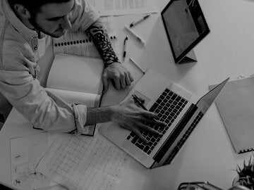 a view from above of a person on their laptop and an open note book