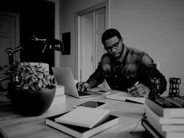 writer using a laptop and taking notes