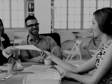 Female accounting passing out financial documents in a meeting.