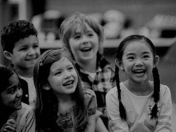 A multi-ethnic group of elementary age children listening to their teacher read a storybook in class.