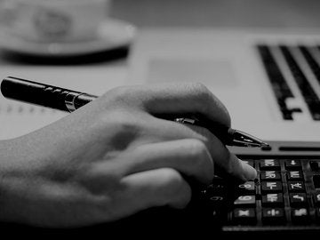 hand holding pen using calculator