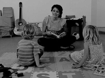 Teacher reading to two kids in class