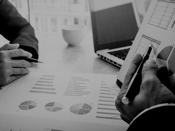 Cropped Image Of Business People Discussing Over Graphs At Table In Office