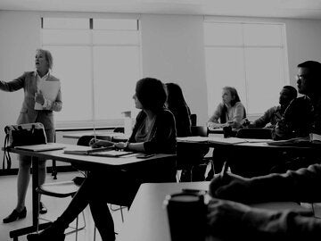Instructor at whiteboard teaching adult education students in classroom