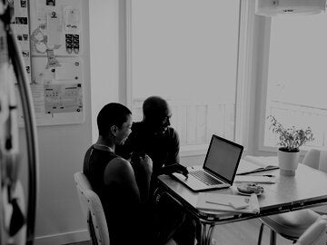 couple looking at a laptop screen at their kitchen table