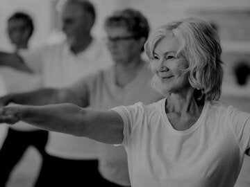 A senior woman is smiling while stretching out her arms.