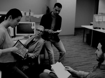 Businesswoman with digital tablet leading meeting at office cubicle