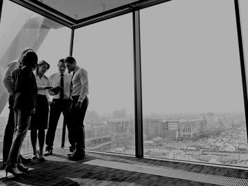 Businesspeople in office with female realtor using digital tablet