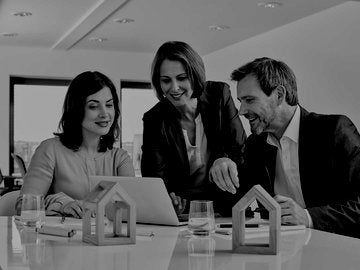 Two Realtors and an intern having a meeting in office with laptop and architectural models