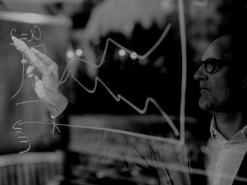 man with glasses writing a calculation on glass