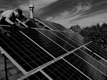 Worker installing solar panels on home roof