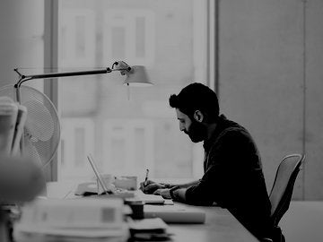 Man working at his desk, writing and reading