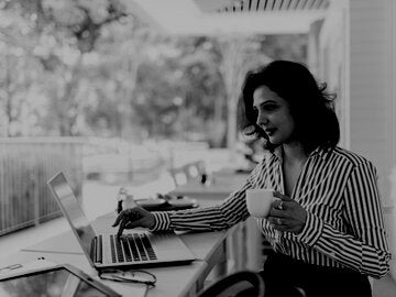 professional woman outside on laptop holding coffee