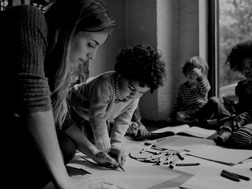 teacher demonstrating art to children