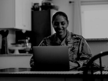 Air Force Service Member at home writing on laptop