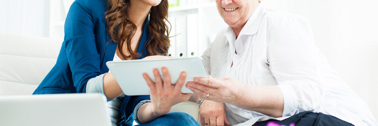 Hospital working showing elderly patient their care options on a tablet.
