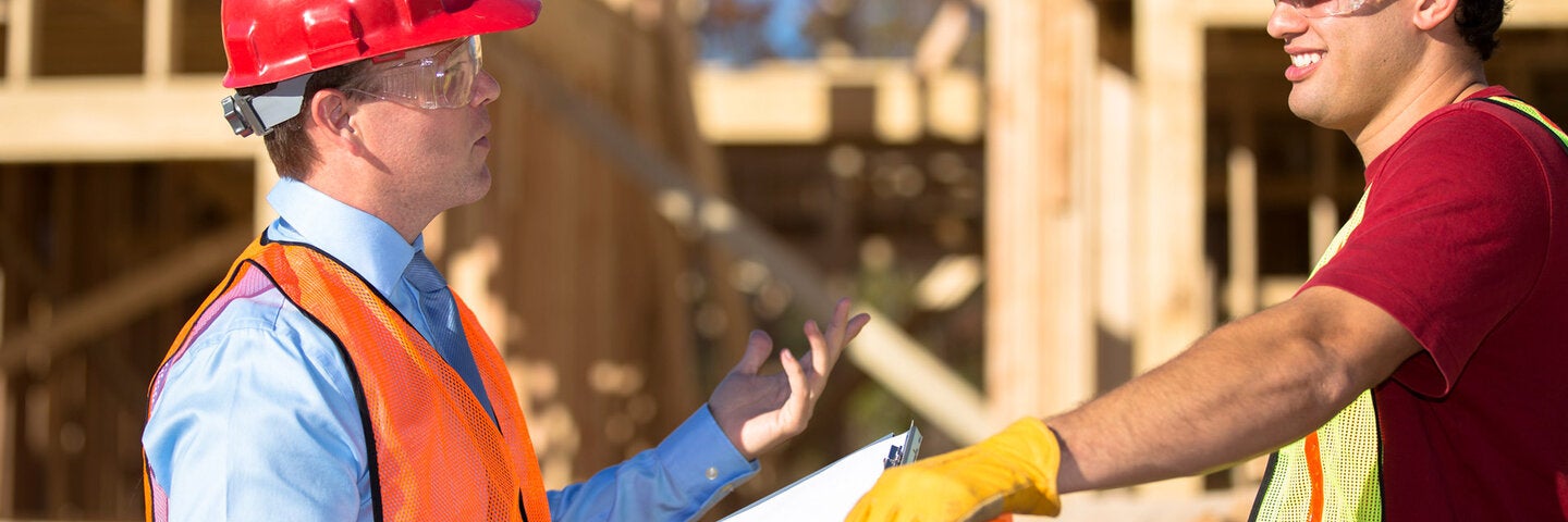 Foreman talking to construction worker on job site.