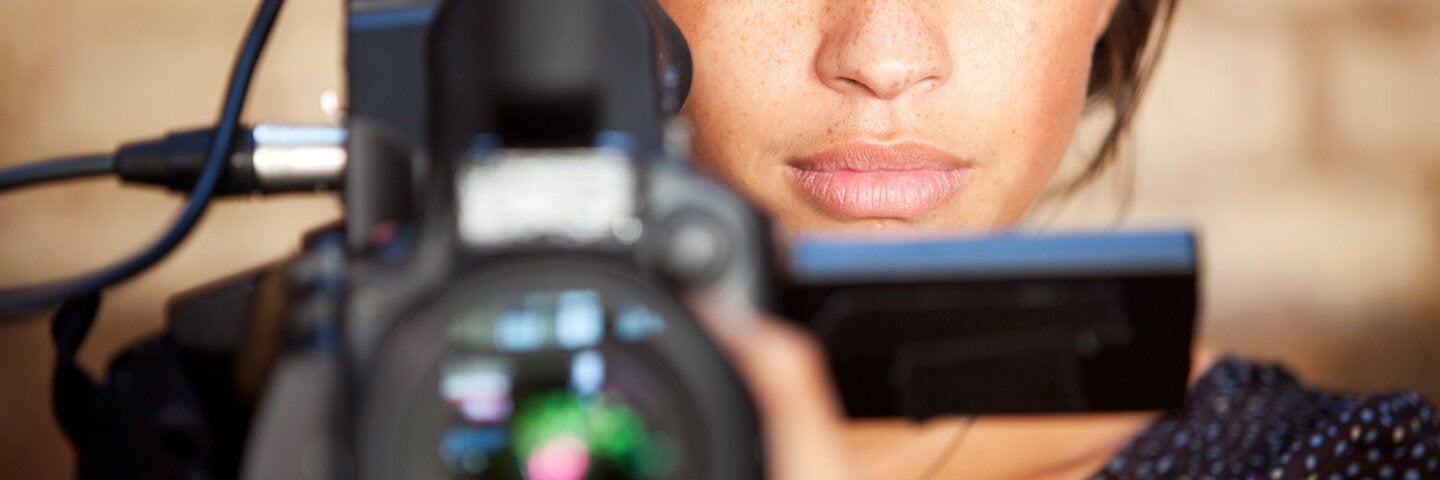 A confident glance from a video camera operator engaging eye contact with her subject during filming.