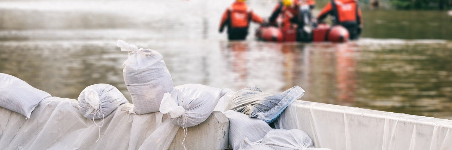 flooded street and sandbags with emergency workers in the background