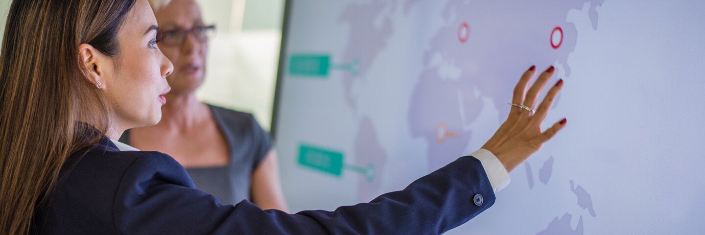 two business women looking at world map