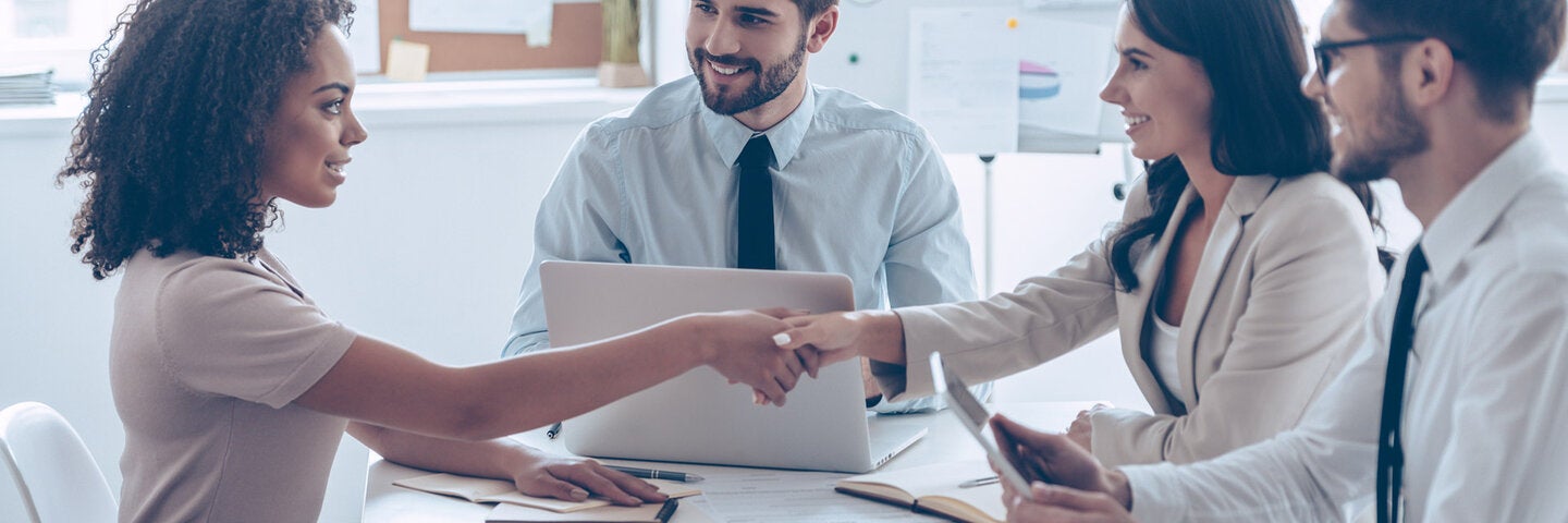 professionals around a table and two shaking hands