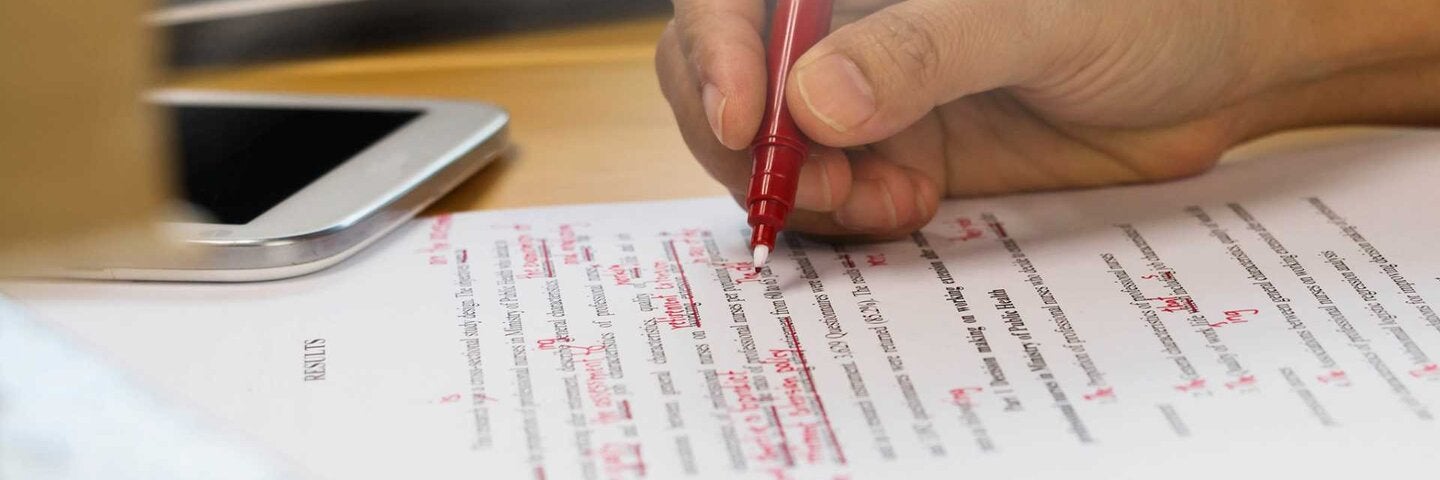 Copywriter making proofreading notes on a print out.