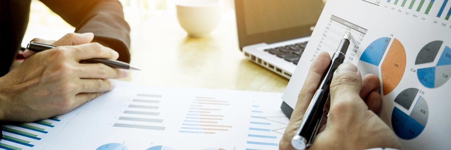 Cropped Image Of Business People Discussing Over Graphs At Table In Office