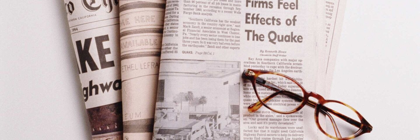 Reading glasses resting on top of newspapers.