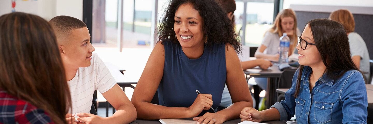 Teacher studying school books in class with high school kids