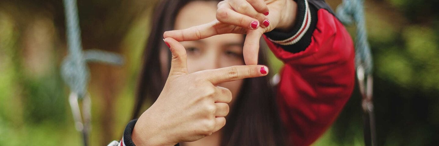 young woman in red making square frame with fingers