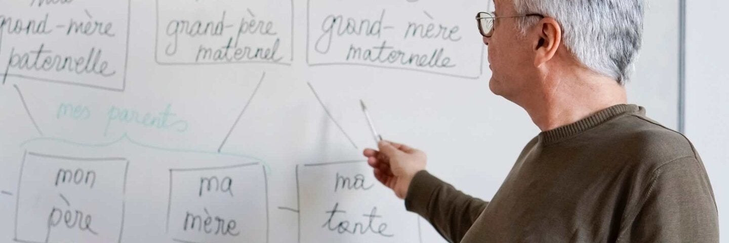 teacher at a whiteboard pointing to French words