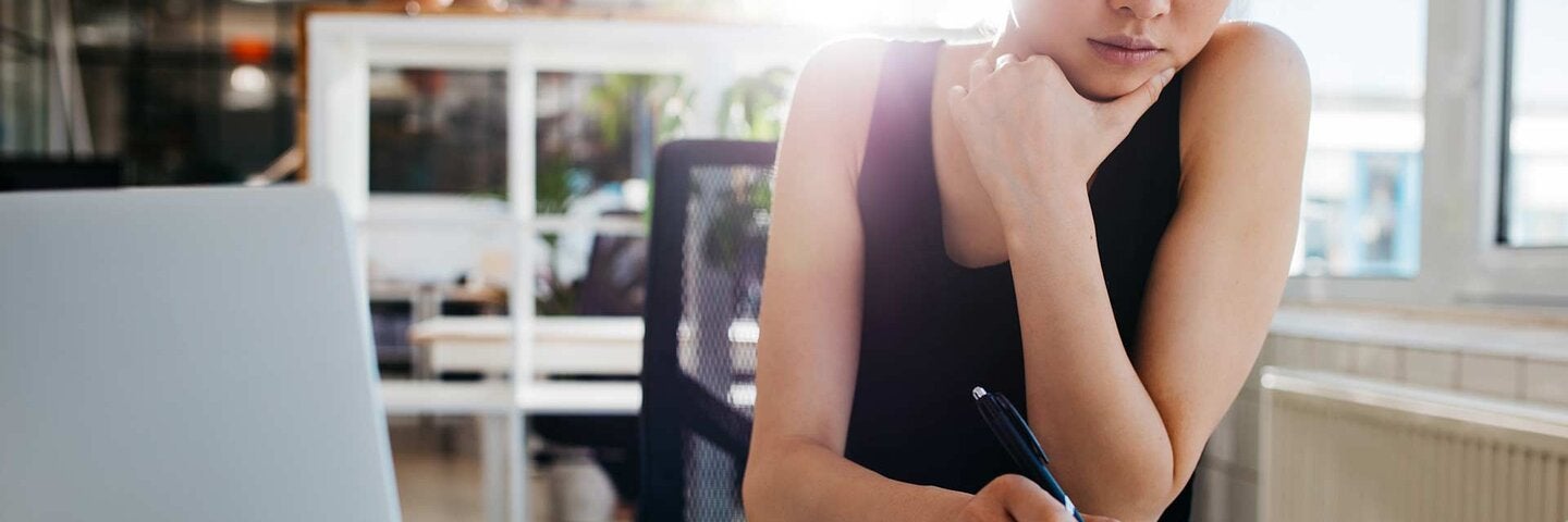 Asian woman writing notes on notepad 