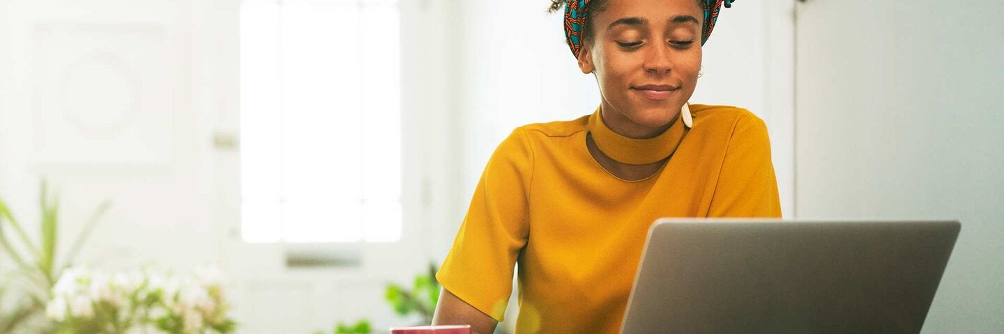 young woman working on her laptop at her home table