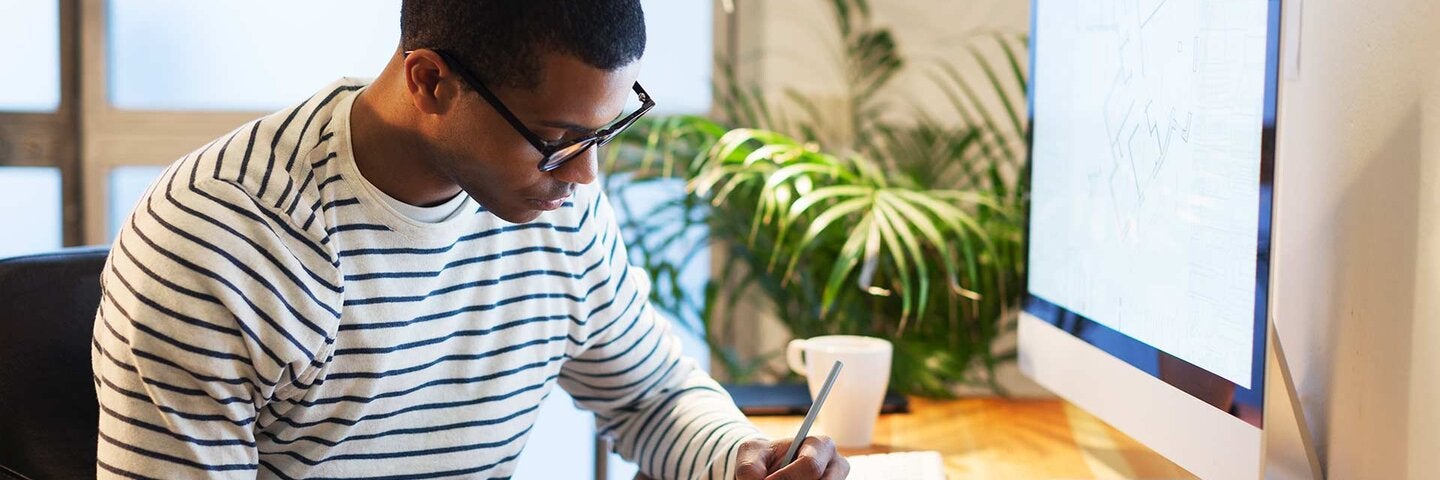 man sitting at desk writing in his notebook