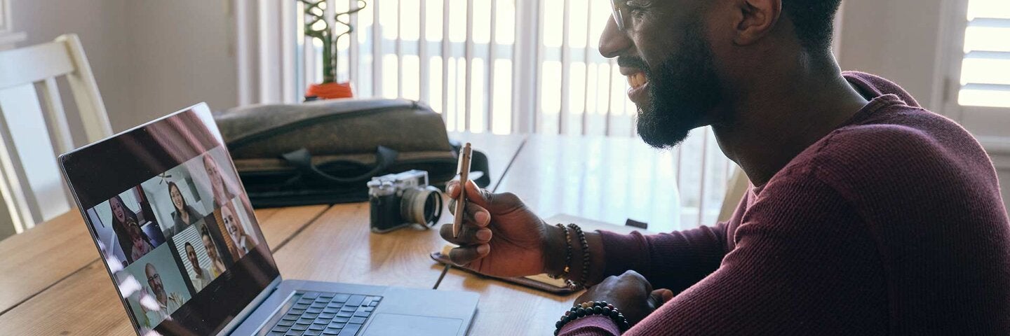 An African American man working at home, participating in a videoconference call on a computer