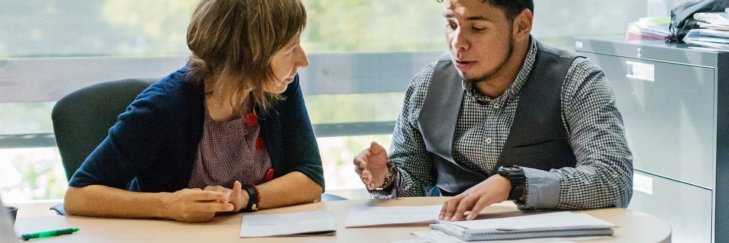 Counseling appointment for young latino man student in counsellor College office.