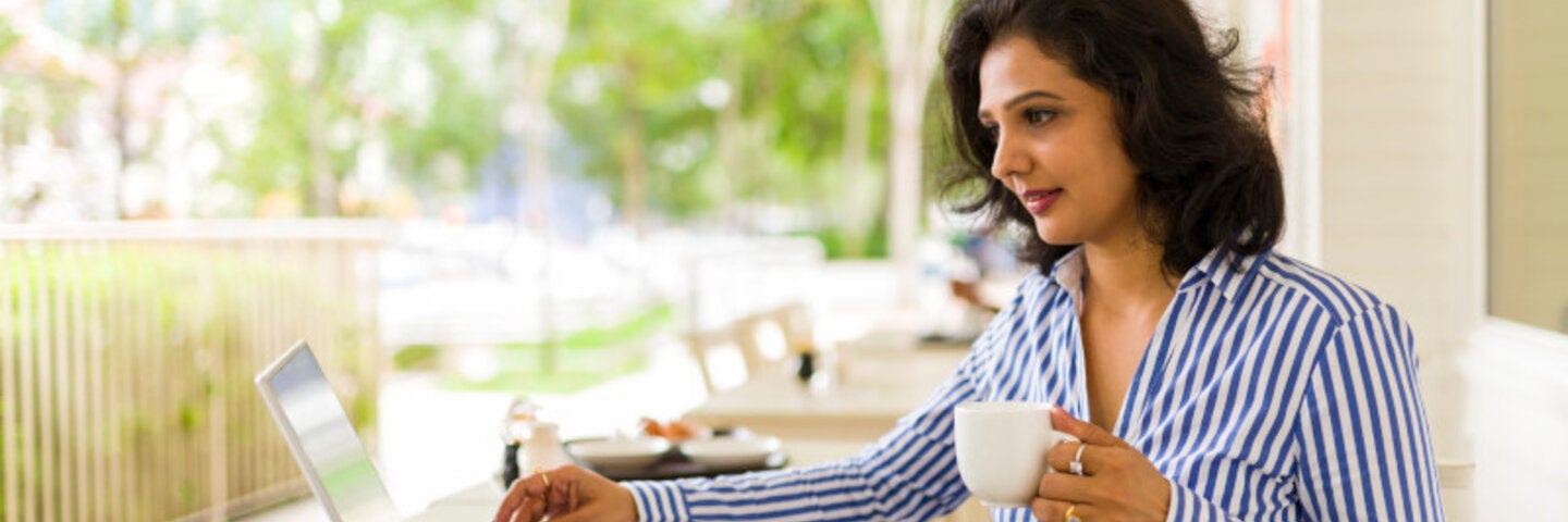 professional woman outside on laptop holding coffee